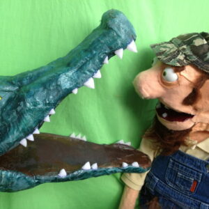 Puppet man looking down open mouth of a crocodile
