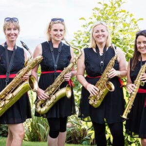 Four ladies stand in a line, dressed in black, holding their saxophones.