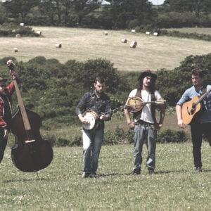 The band stand with their instruments in a field.